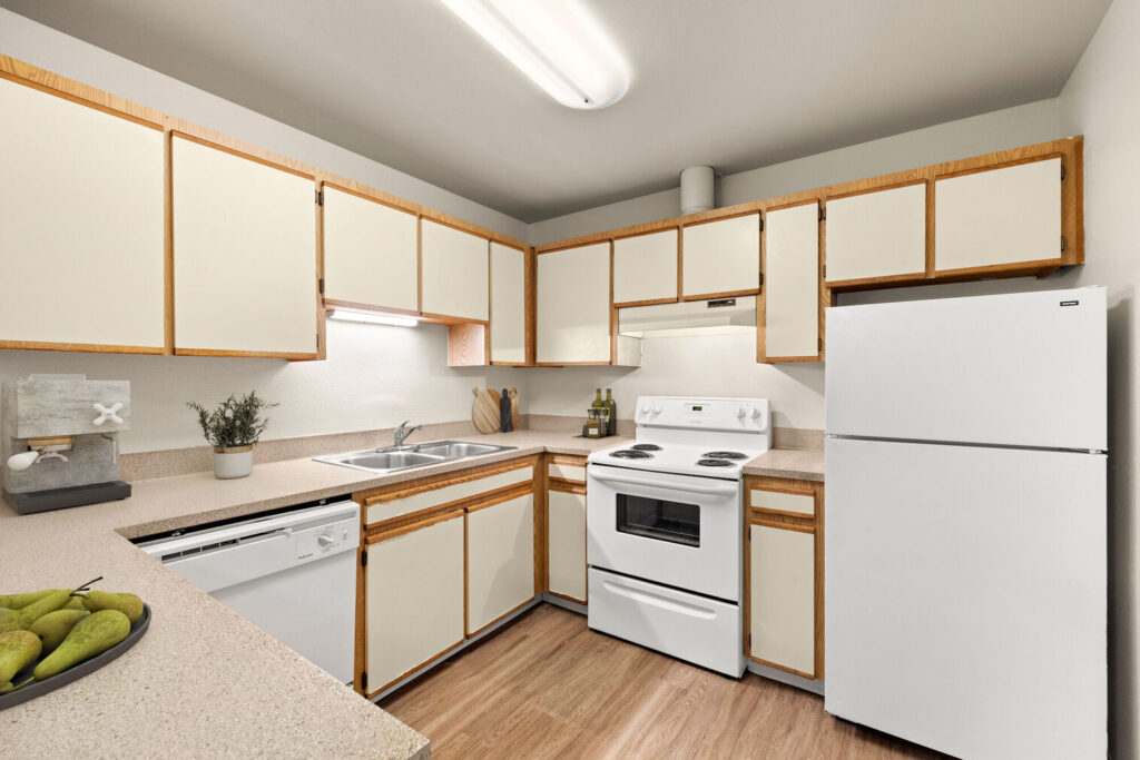 Kitchen with white appliances and tan cabinets at Lake Crest apartments in Milwaukie