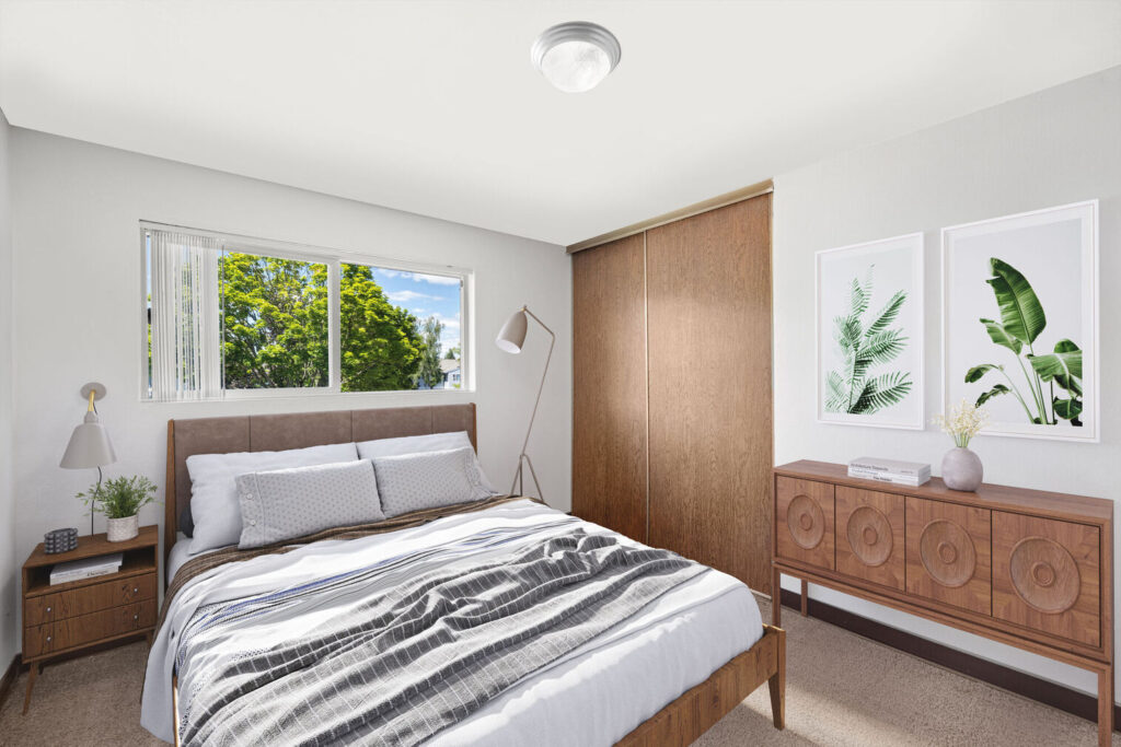 Furnished bedroom with a window and art on the wall at Lake Crest apartments in Milwaukie, Oregon